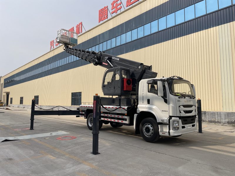 Technician performing winter maintenance on an aerial work vehicle in snow. Aerial Work Vehicles